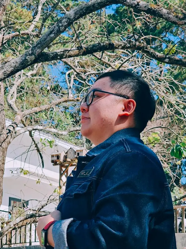 Nguyễn Tấn Thiên Long, áo khoác jean, đứng dưới tán thông